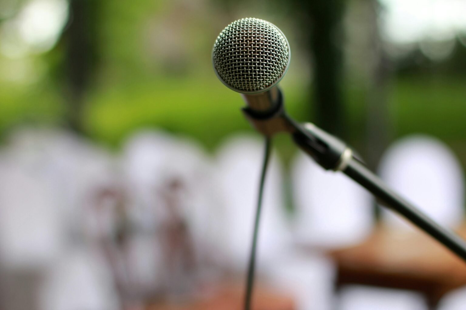 Focused view of a microphone on a stand outdoors, ready for a performance.
