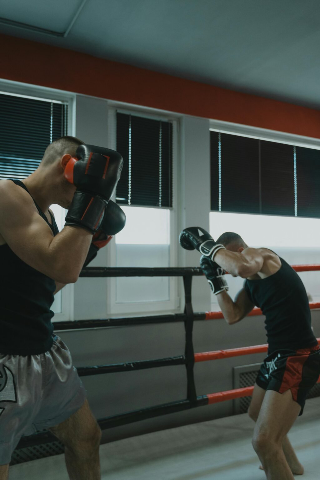 Two men engaged in a dynamic boxing sparring match inside a gym.